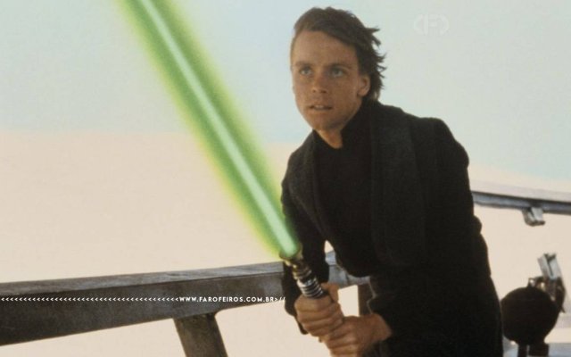 Cena de Star Wars: O Retorno de Jedi. Luke Skywalker jovem, de roupa preta, segura seu sabre de luz verde com ambas as mãos em posição de combate, com expressão tensa. O cenário é um deserto com o fundo claro e desfocado. Na parte inferior, a marca d'água do site www.farofeiros.com.br