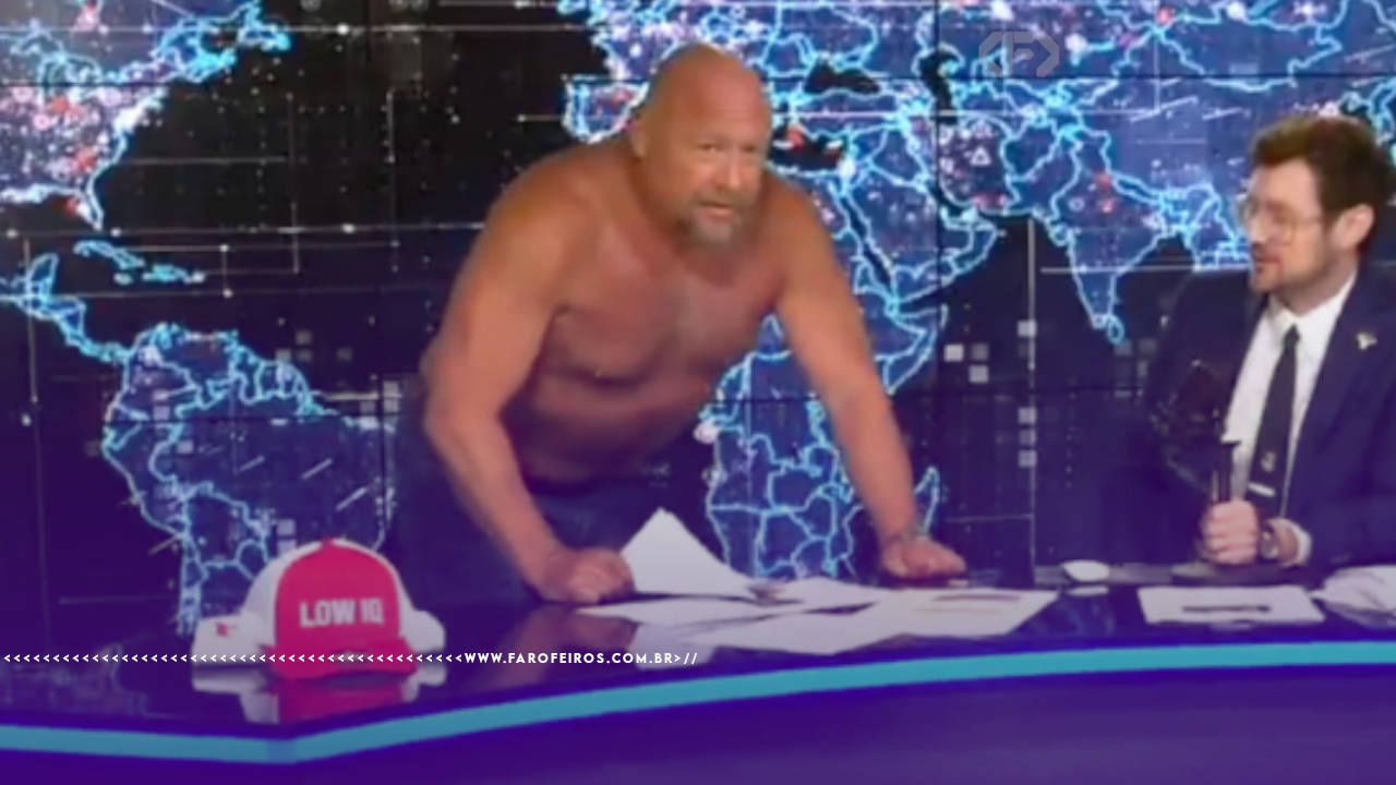 Captura de transmissão do conspiracionista de extrema direita Alex Jones no cenário do seu InfoWars sem camiseta e sem cabelo. Sua musculatura flácida e careca chamam a atenção enquanto ele apoia as mãos na mesa e é olhado pelo âncora do lado direito. O cenário é iluminado em azul com um mapa mundi brilhante. Na parte inferior, a marca d'água do site www.farofeiros.com.br