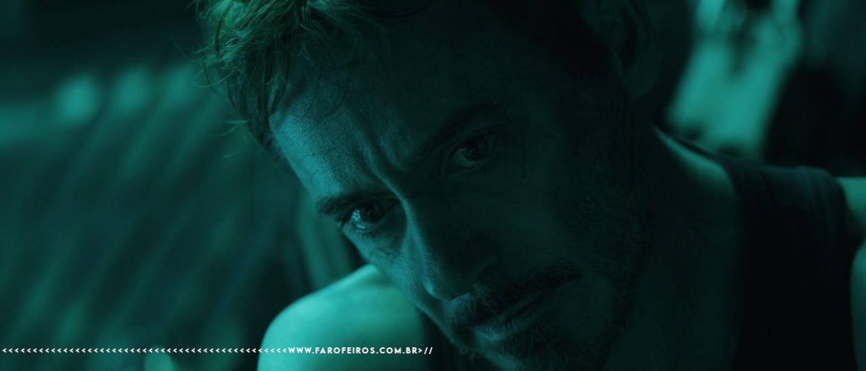 Cena do filme Vingadores: Ultimato com iluminação esverdeada. Close no rosto de Tony Stark, interpretado por Robert Downey Jr., com expressão abatida e exausta, olhando para baixo. Na parte inferior, a marca d'água do site www.farofeiros.com.br