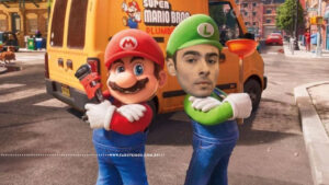 Montagem humorística com cena do filme "Super Mario Bros." (2023): Mario animado à esquerda e, no lugar de Luigi, o rosto de um homem real fotomontado sobre o personagem animado com roupa verde e boné com "L". O rosto é de Luigi Mangione. Ao fundo, a van amarela da Mario Bros. Plumbing. Marca d'água do site Farofeiros.com.br na parte inferior.