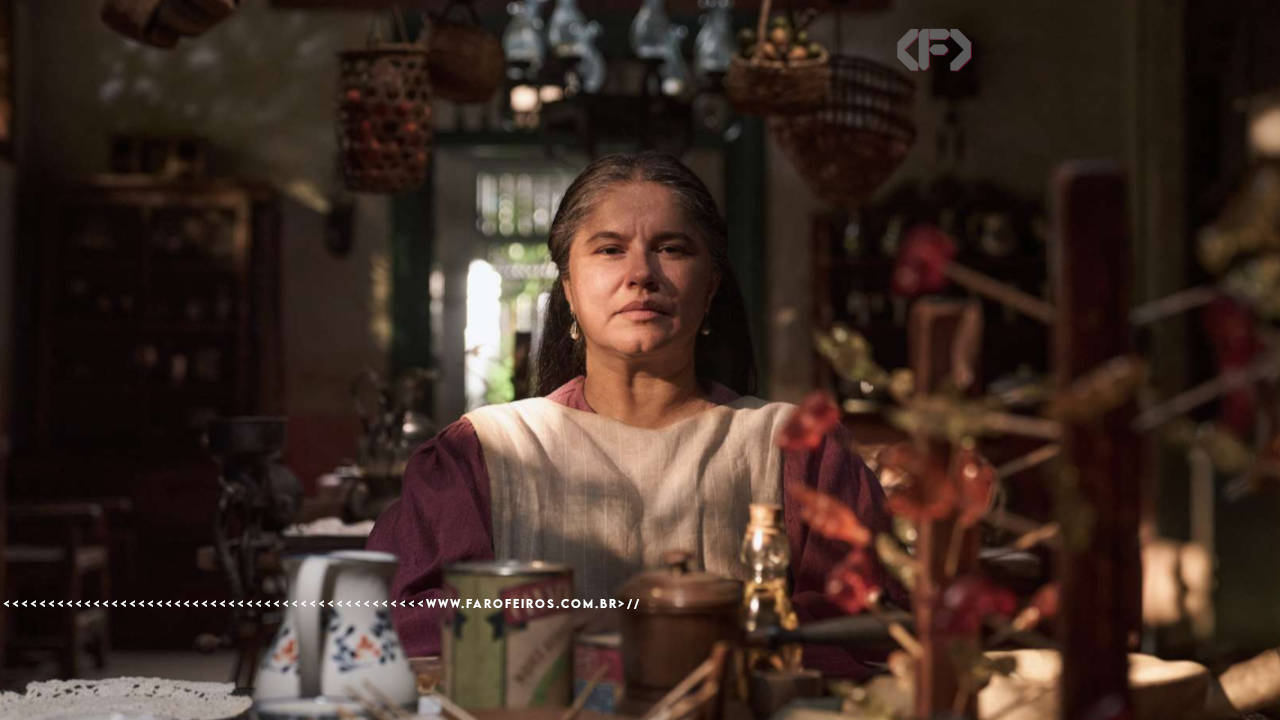 Foto da série Cem Anos de Solidão mostrando Úrsula sentada à mesa com um olhar firme mas terno