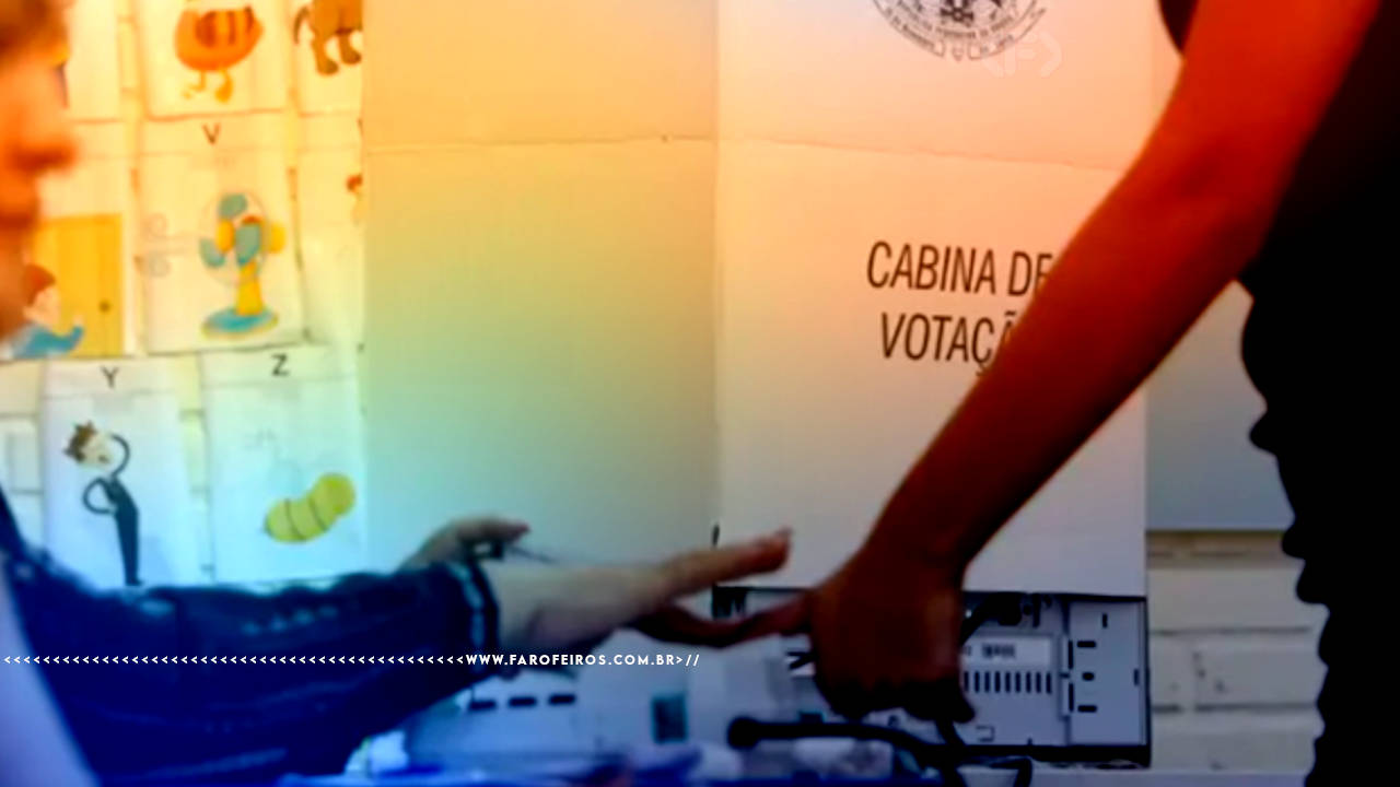 Fotografia em uma zona eleitoral com uma pessoa confirmando a digital a frente de uma cabina de votação